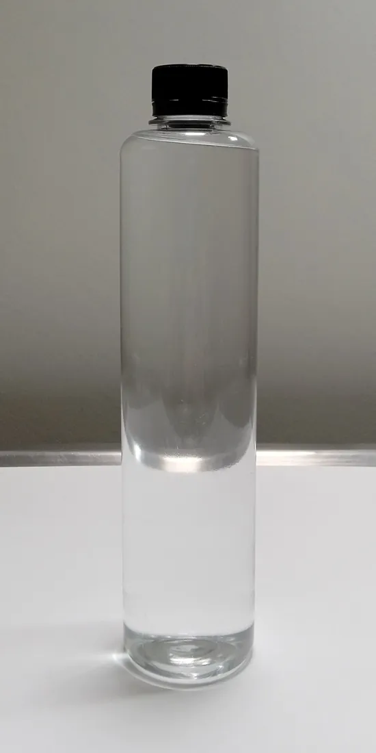 Clear transparent cylindrical reusable water bottle with black screw-on cap on a white surface